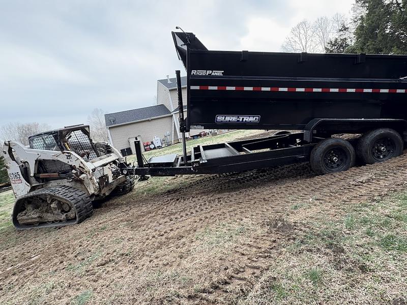 Bobcat S185 track loader and a Sure-Trac dump trailer parked on a freshly graded residential back yard