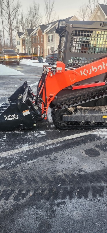 Kubota compact track loader with brush cutter attachment clearing overgrown vegetation